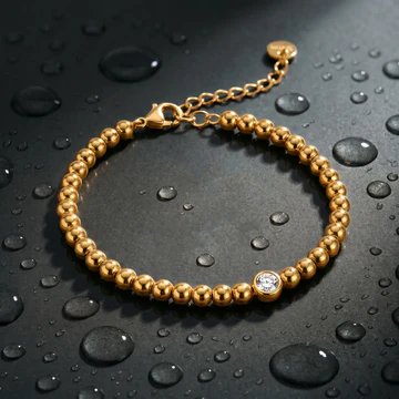 Gold beaded bracelet with a single solitaire on dark slate