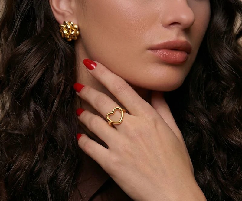 Model wearing gold knot earrings and heart ring from the Demifine collection