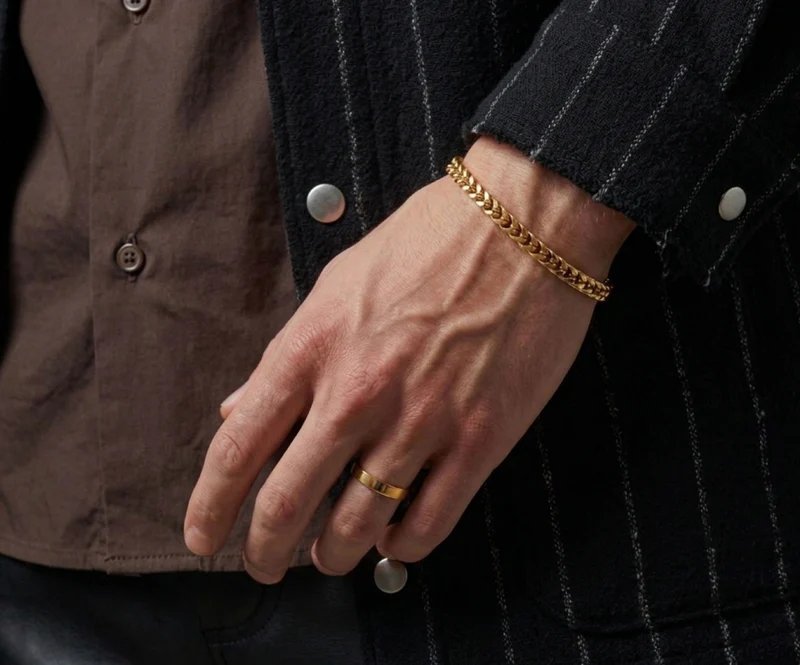 Man wearing a gold curb chain bracelet and band ring from the men's line